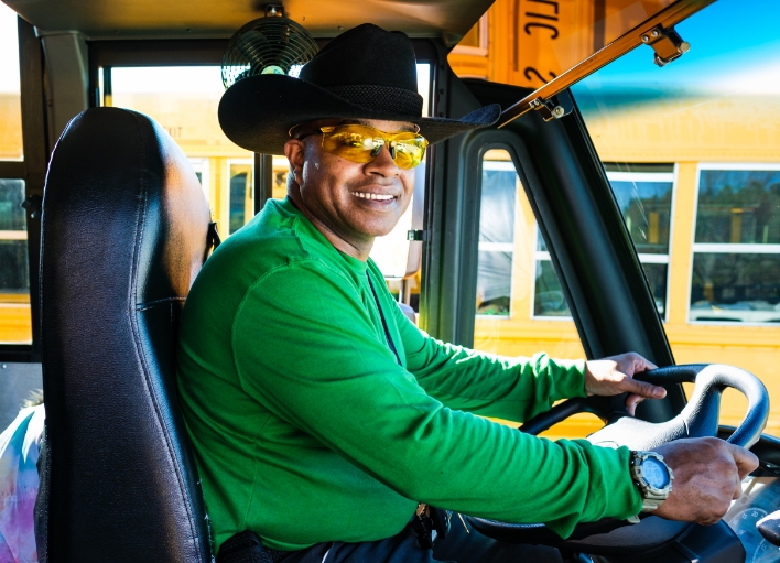 Student waves outside a yellow school bus