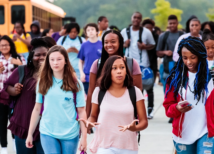 A group of students smiling after getting off a school bus.