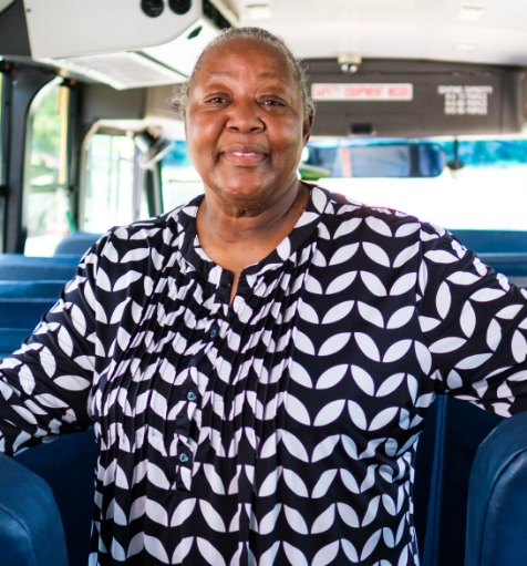 A Bus Safety Assistant standing on a school bus and smiling.